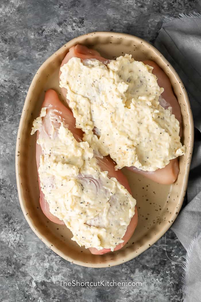 raw chicken with cheese sauce in a baking dish