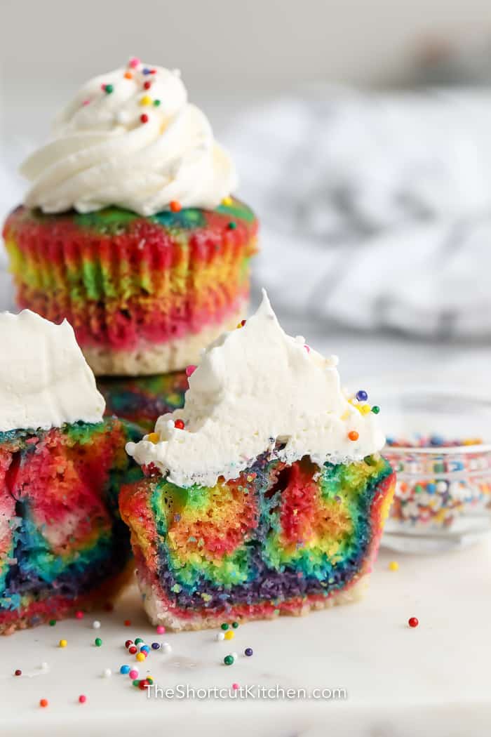 group of rainbow coloured cupcakes on a cutting board