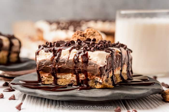 slice of Chocolate Chip Cookie Lasagna on a plate with a glass of milk beside it