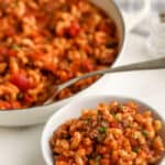 American Goulash served in a white bowl, with a white pan in the background,