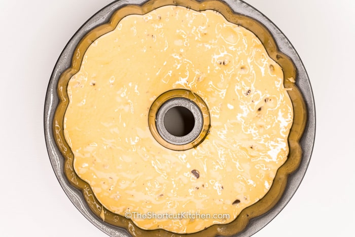 Chocolate chip bundt cake brings together easy ingredients to create a dessert everyone loves. The batter is smooth and rich with vanilla flavor and loaded with chocolate chips for sweet chocolate in every bite. It bakes into a fluffy cake that holds its shape perfectly when flipped from the pan. This is the kind of recipe you will make again and again for gatherings and celebrations. #theshortcutkitchen Chocolate Chip Bundt Cake batter in a cake pan