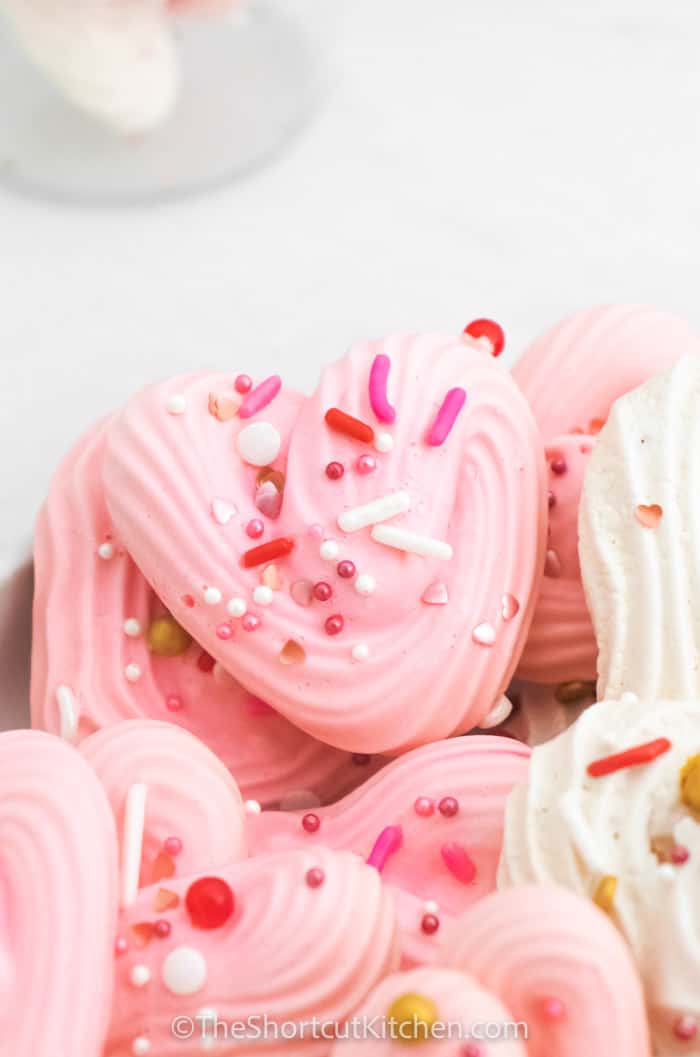 close up of pink and white Heart Meringues with sprinkles