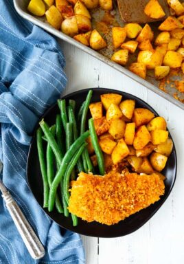 chicken, potatoes and green beans on a plate next to a blue napkin