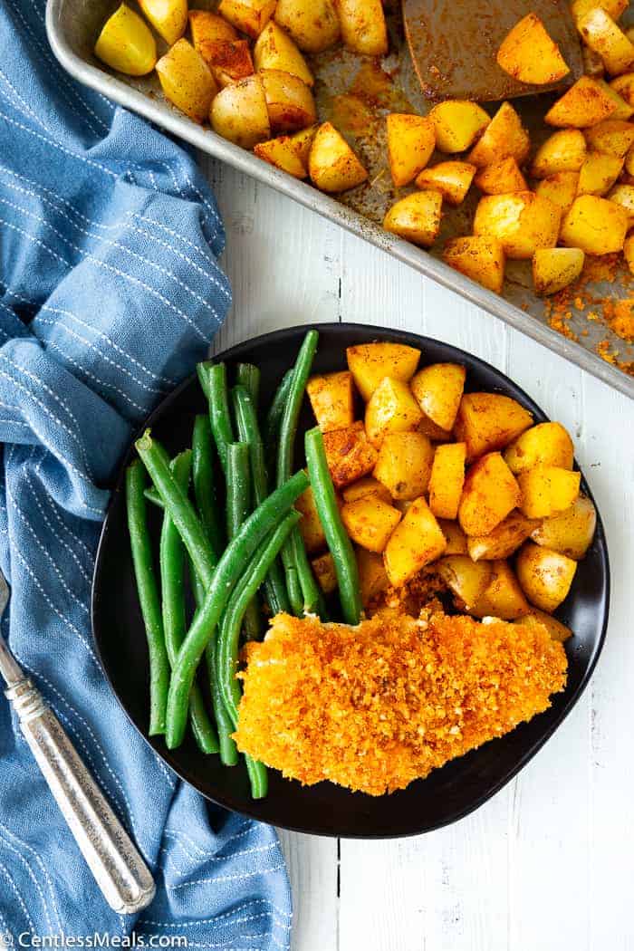 chicken, potatoes and green beans on a plate next to a blue napkin