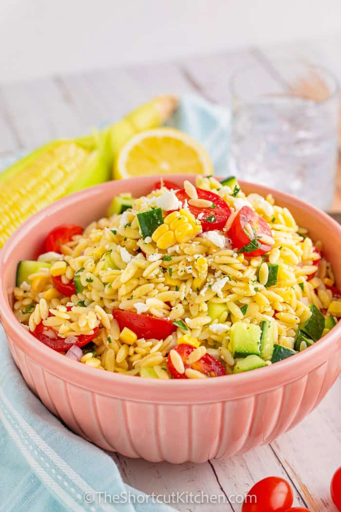 plated Orzo Pasta Salad with corn and lemon in the back
