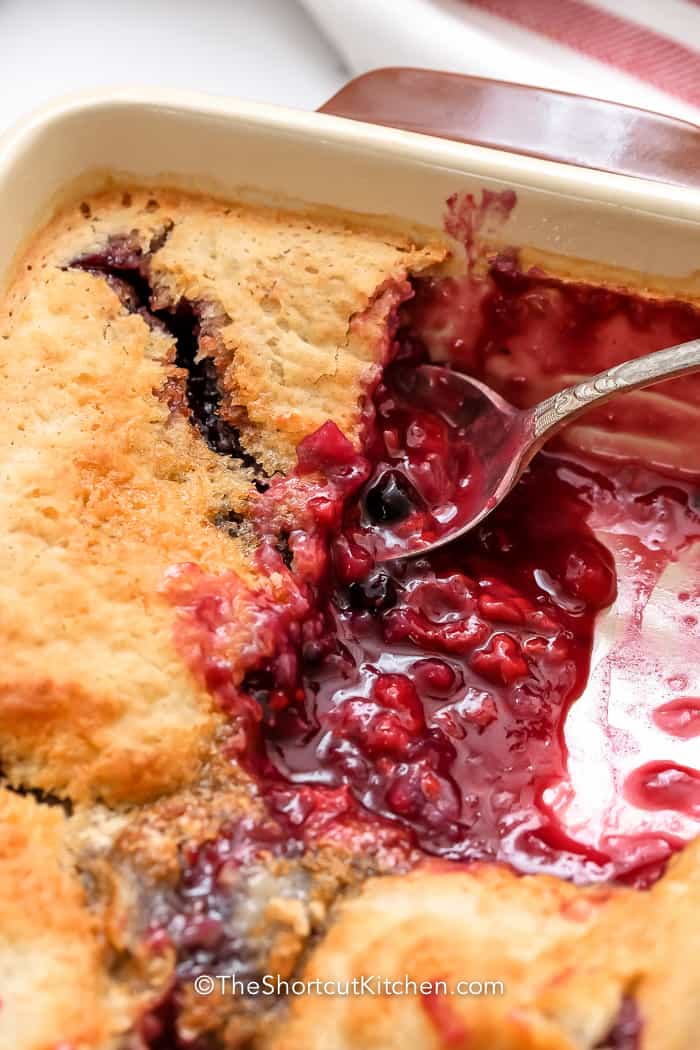 spoon scooping Mixed Berry Dump Cake in a dish