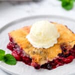 Mixed Berry Dump Cake on a plate topped with ice cream