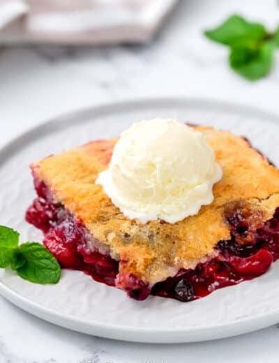 Mixed Berry Dump Cake on a plate topped with ice cream