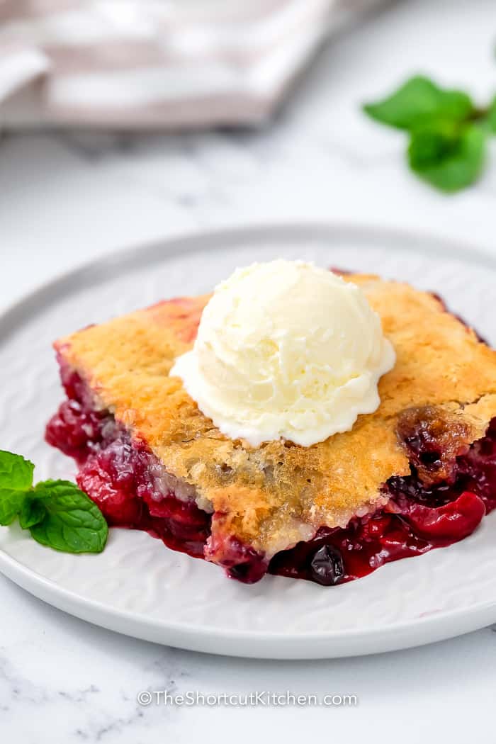 Mixed Berry Dump Cake on a plate topped with ice cream