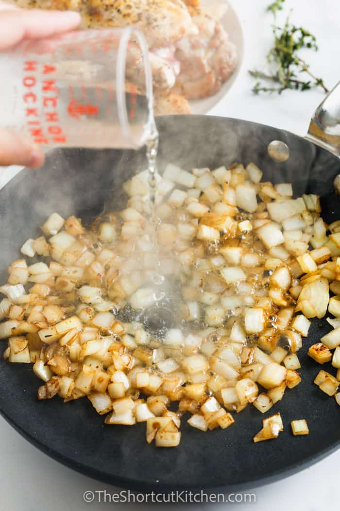 onions being cooked in a frying pan for creamy crockpot chicken thighs with mushrooms