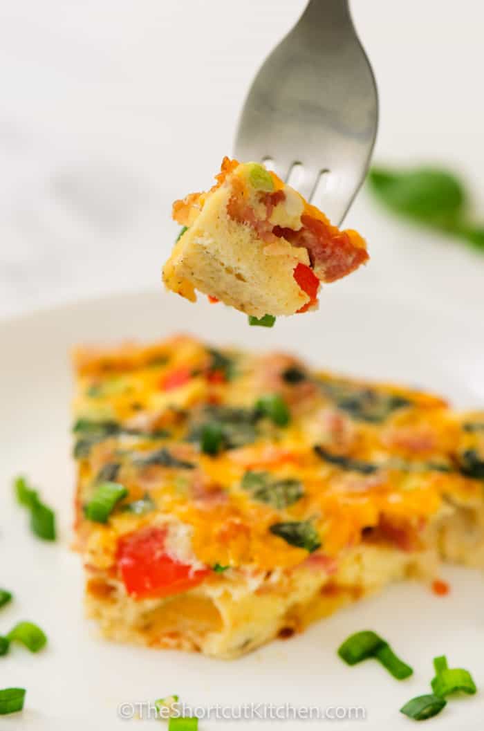 fork with a bite of Egg Frittata on it with plated dish in the back