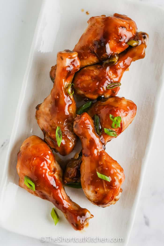 A plate of soy sauce chicken drumsticks garnished with green onions
