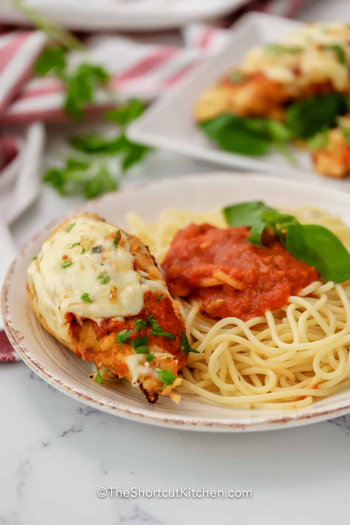 Air Fryer Parmesan Chicken served over spaghetti with basil