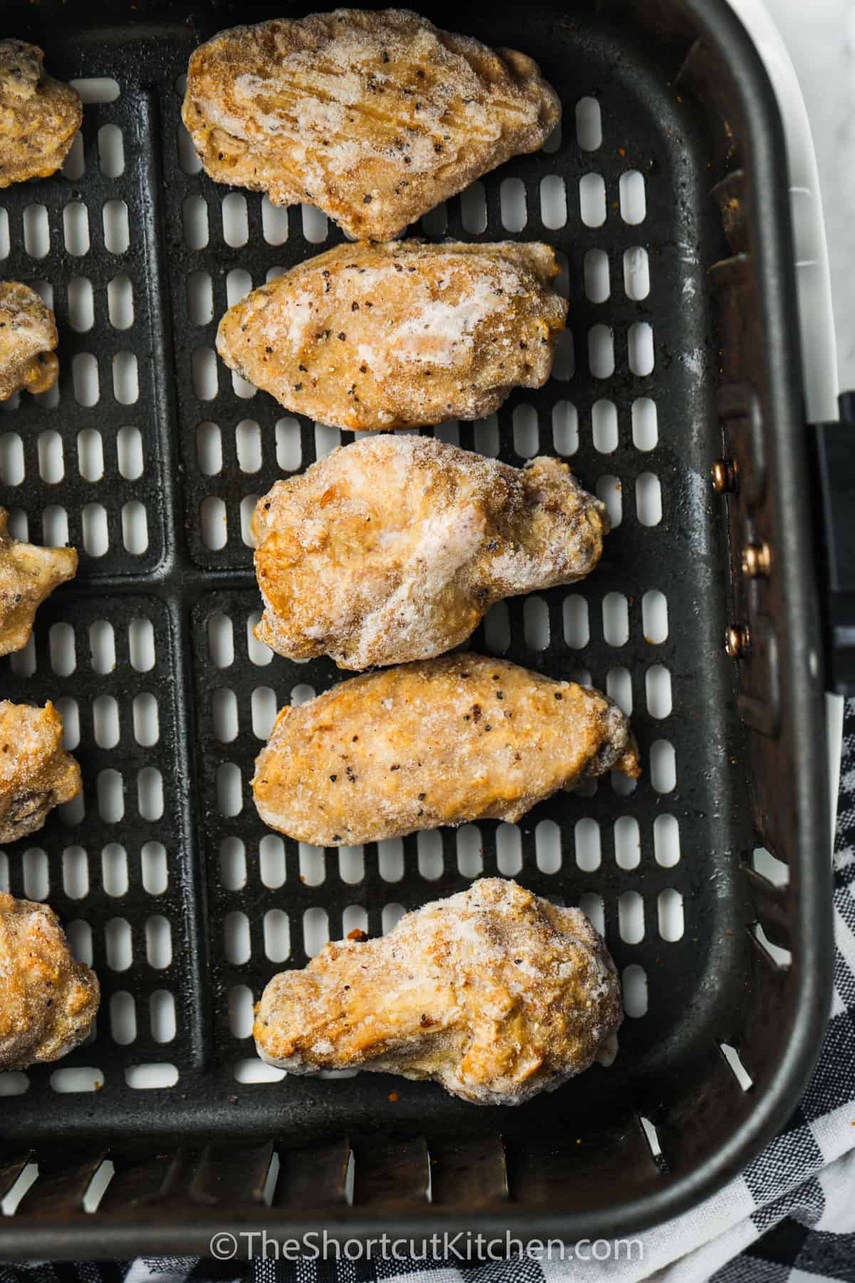 Frozen chicken wings in an air fryer basket