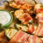 Bacon Wrapped Stuffed Jalapenos on a plate with dip