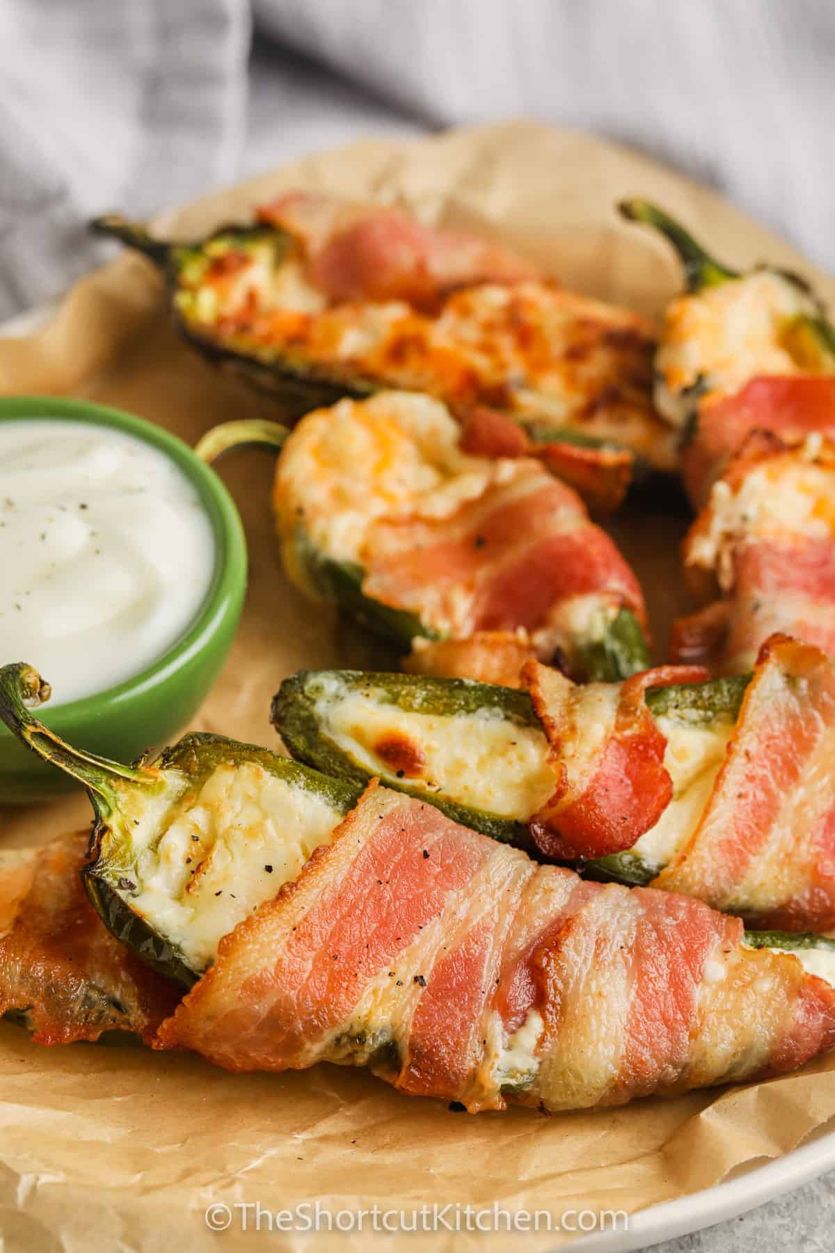 Bacon Wrapped Stuffed Jalapenos on a plate with dip