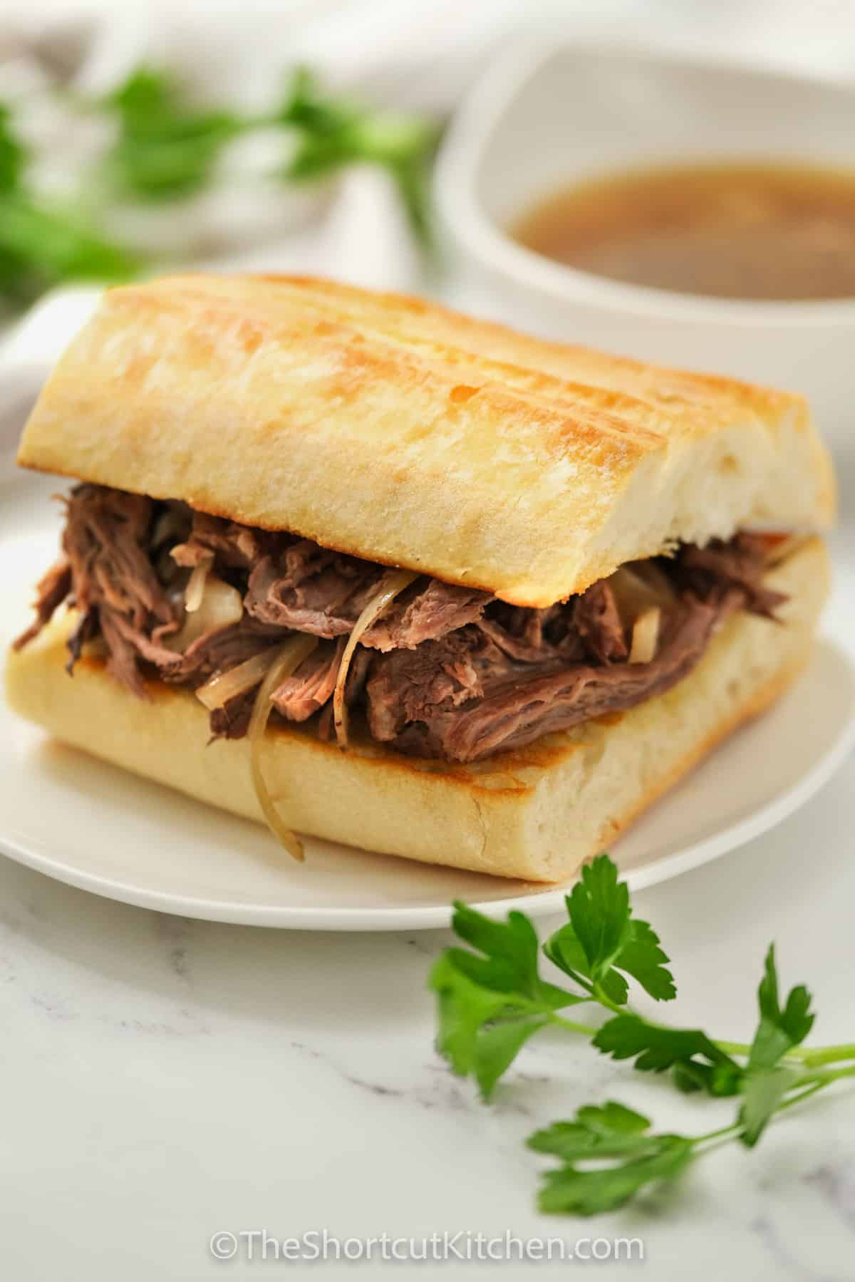 plated Crock Pot French Dip Recipe with dip in the back