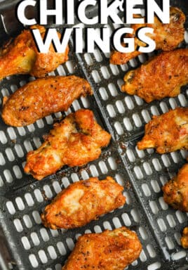 Cooked chicken wings in an air fryer basket with writing