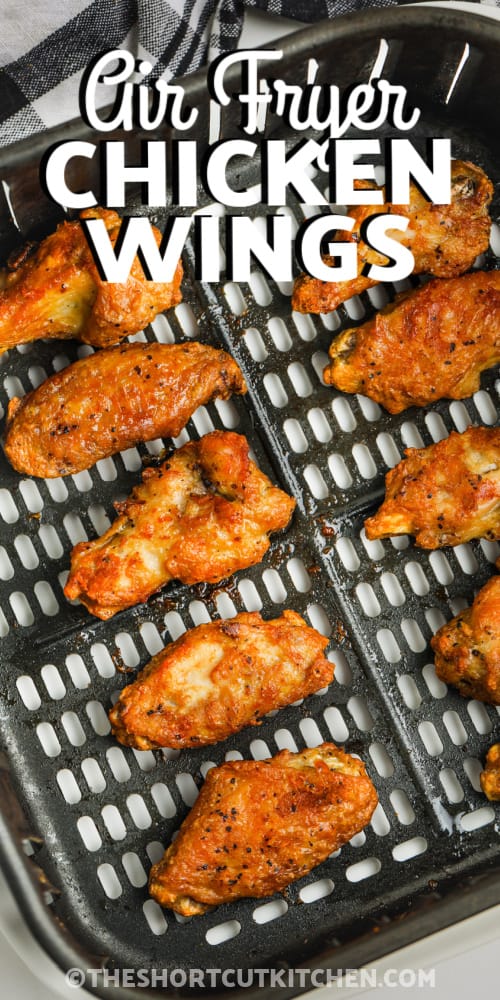 Cooked chicken wings in an air fryer basket with writing