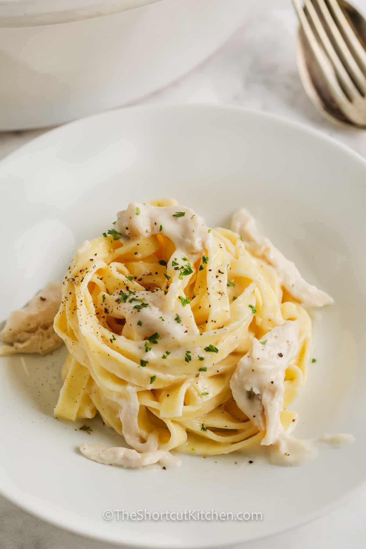 crockpot chicken alfredo served on a white plate, garnished with fresh parsley