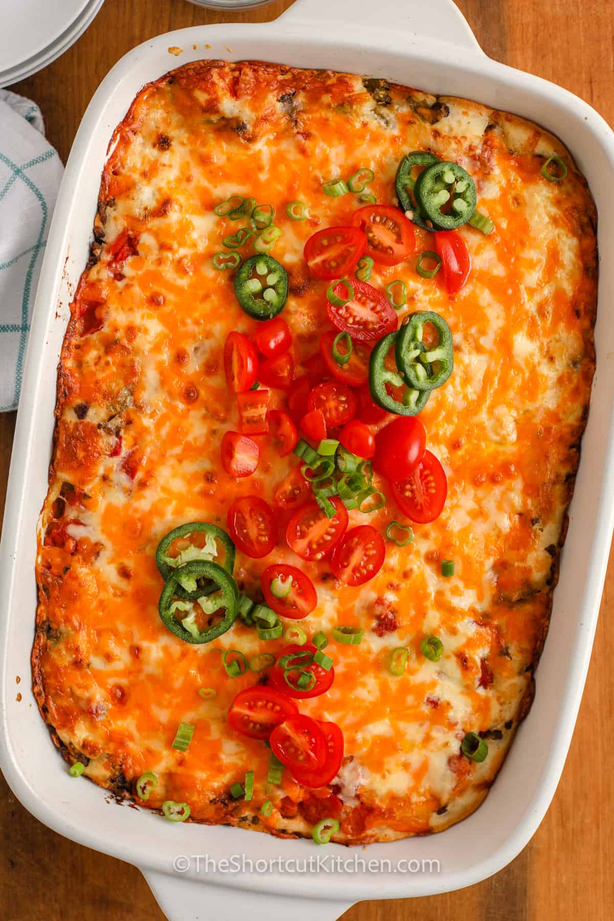 John Wayne Casserole in a white casserole dish with tomatoes and jalapenos
