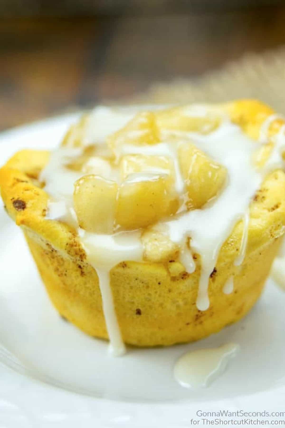 A Cinnamon Roll Apple Pie Bites on a white plate drizzled with icing