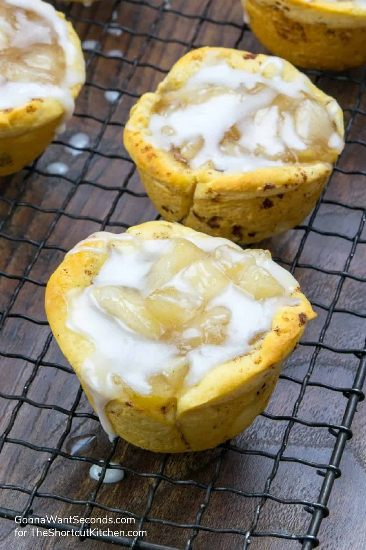 Cinnamon Roll Apple Pie Bites on a wire rack with icing drizzled over top