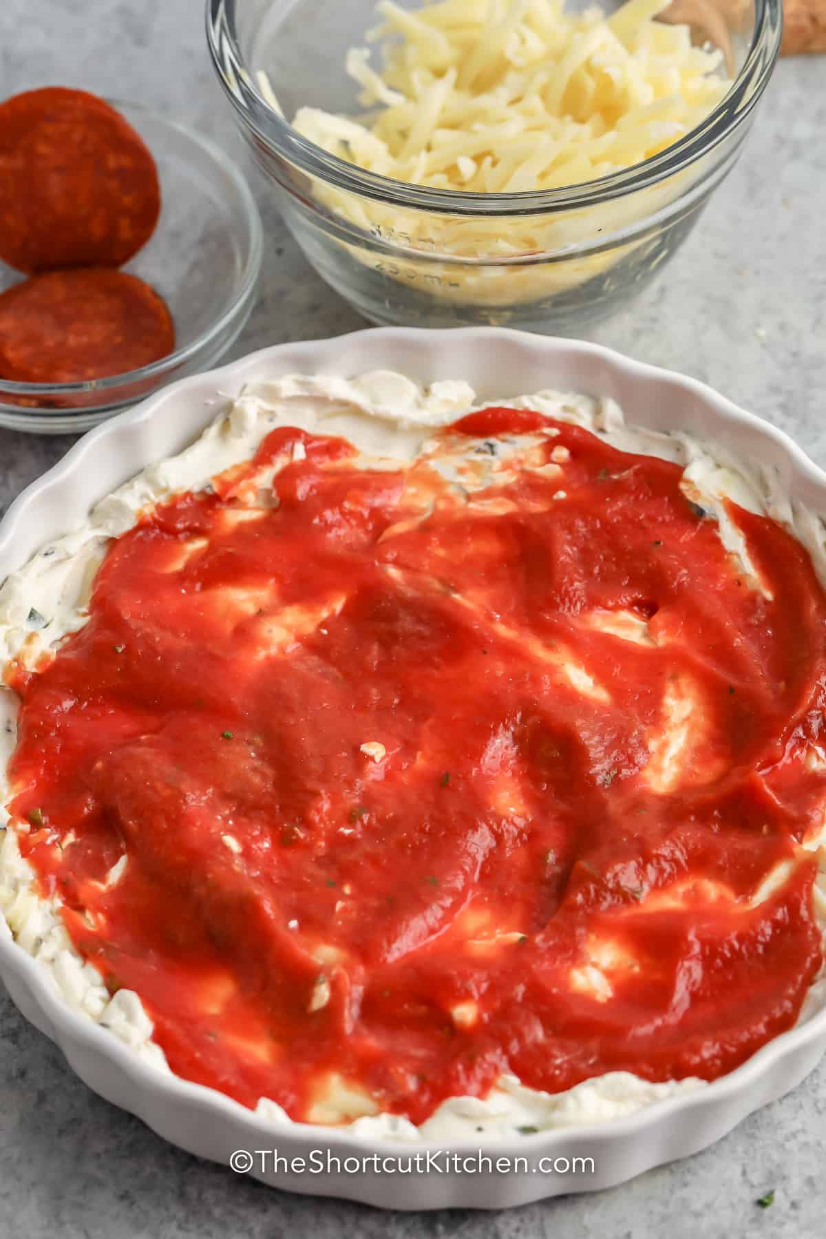 Cream cheese mixture topped with pizza sauce in a serving dish