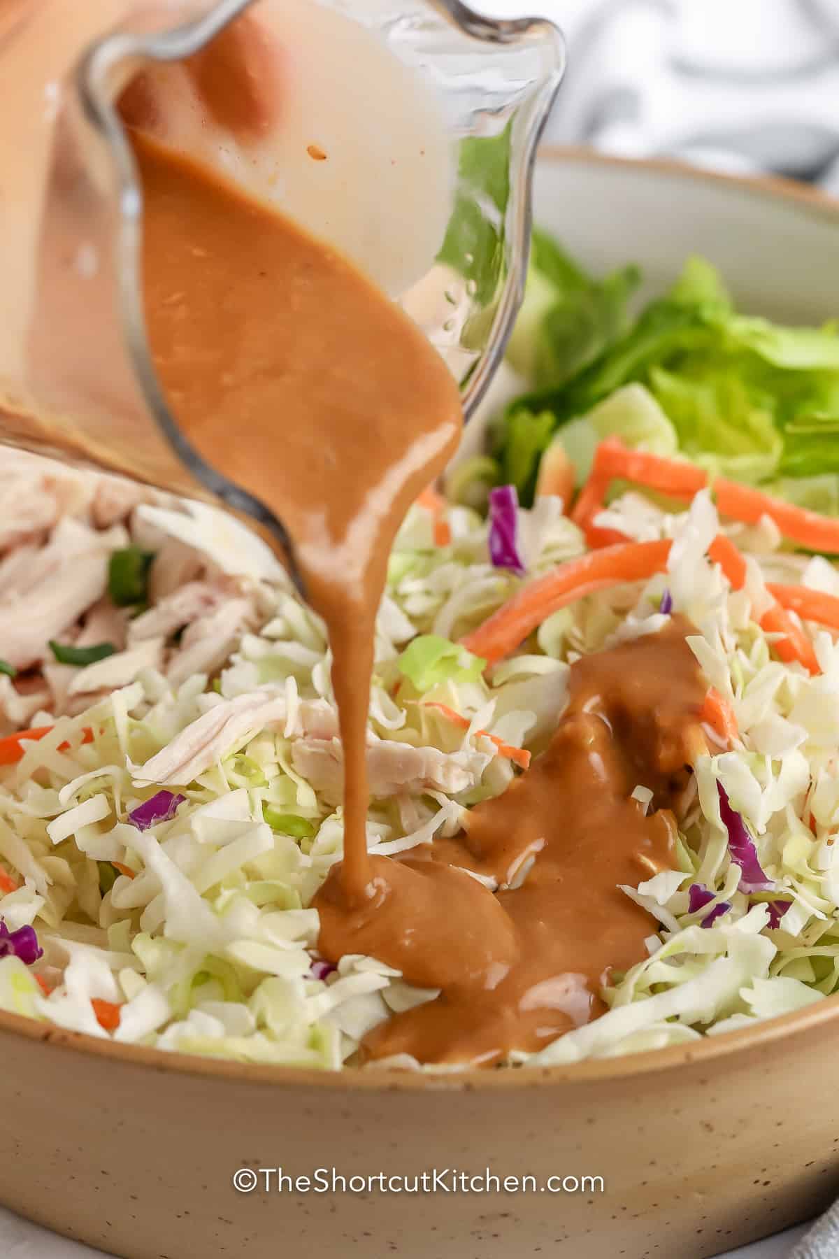pouring dressing on Asian Chicken Salad
