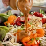 Mandarin Chicken Salad in a bowl with dressing being poured on