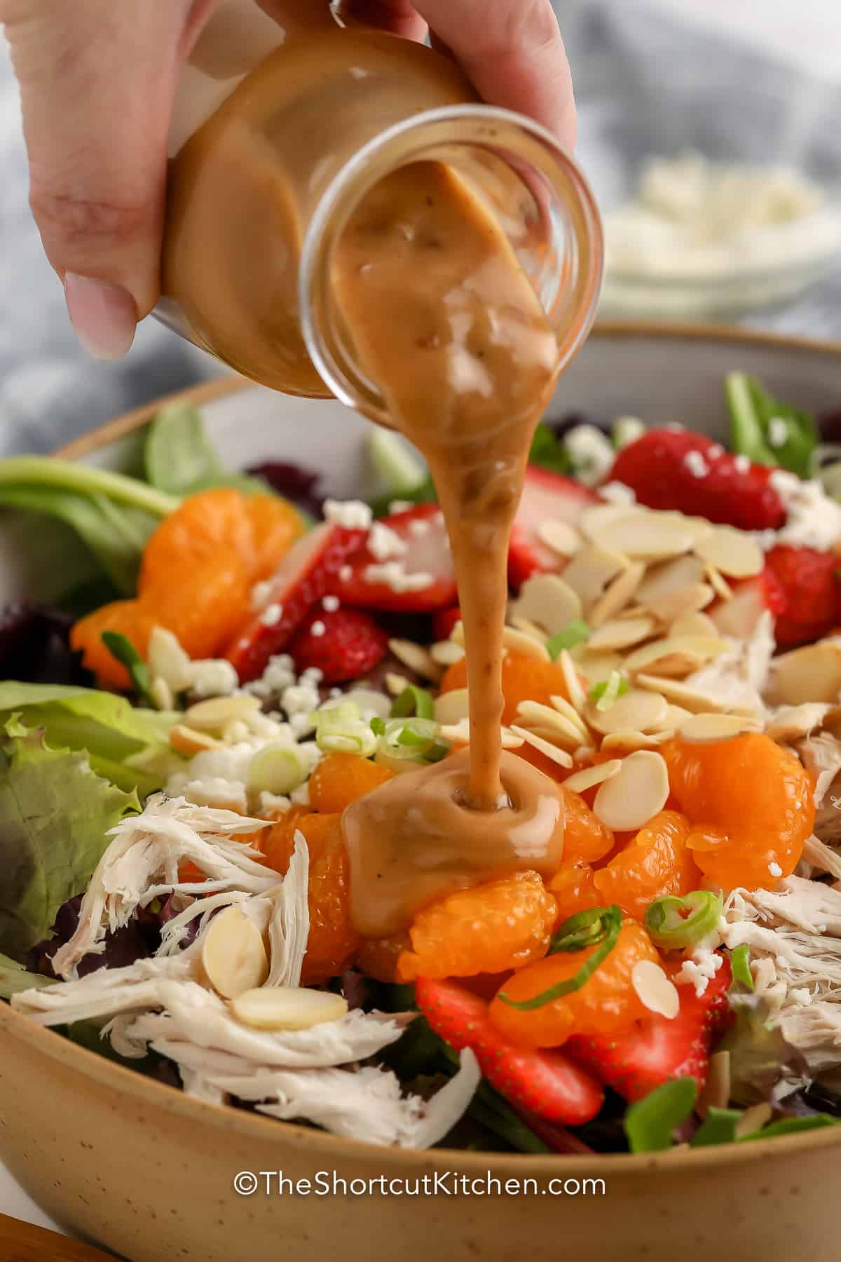Mandarin Chicken Salad in a bowl with dressing being poured on