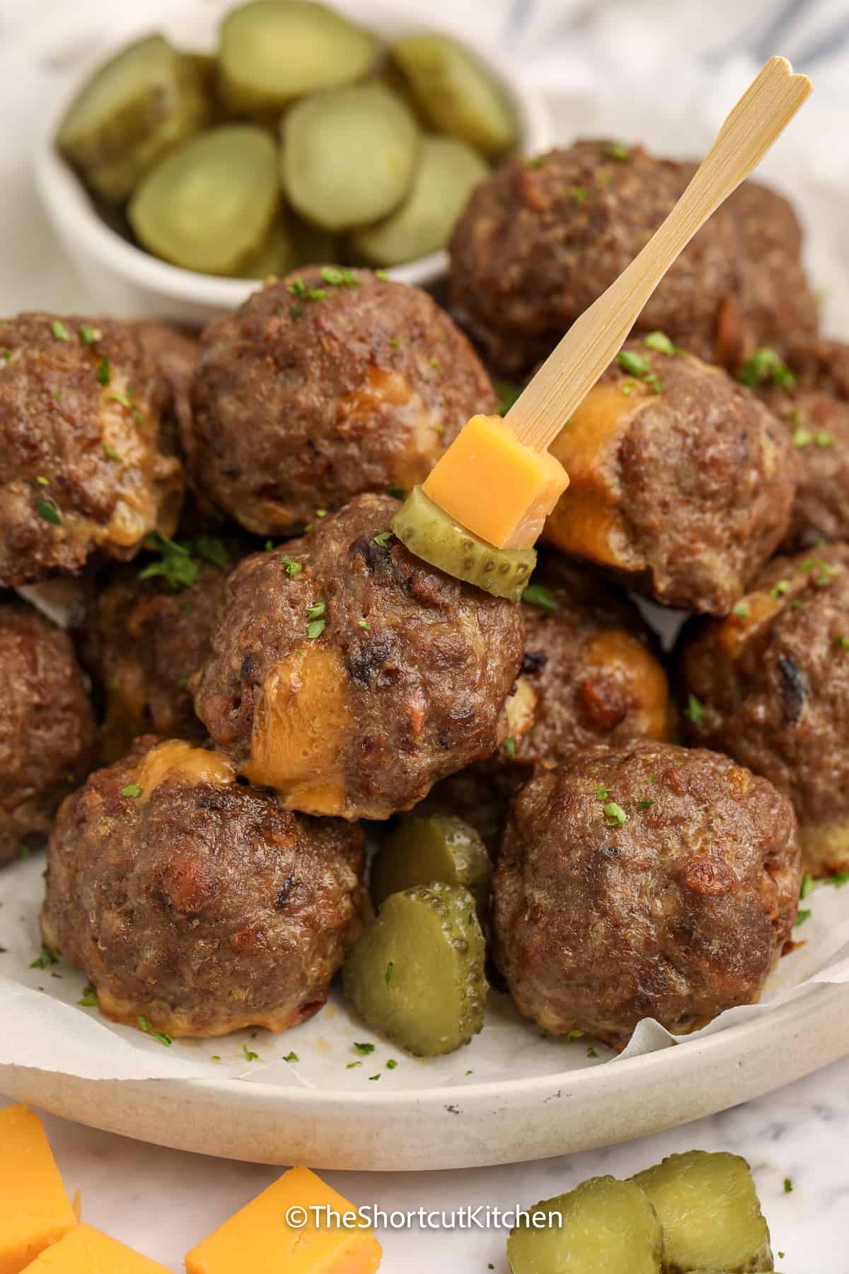 bacon cheeseburger meatballs on a plate with pickle slices and cheese