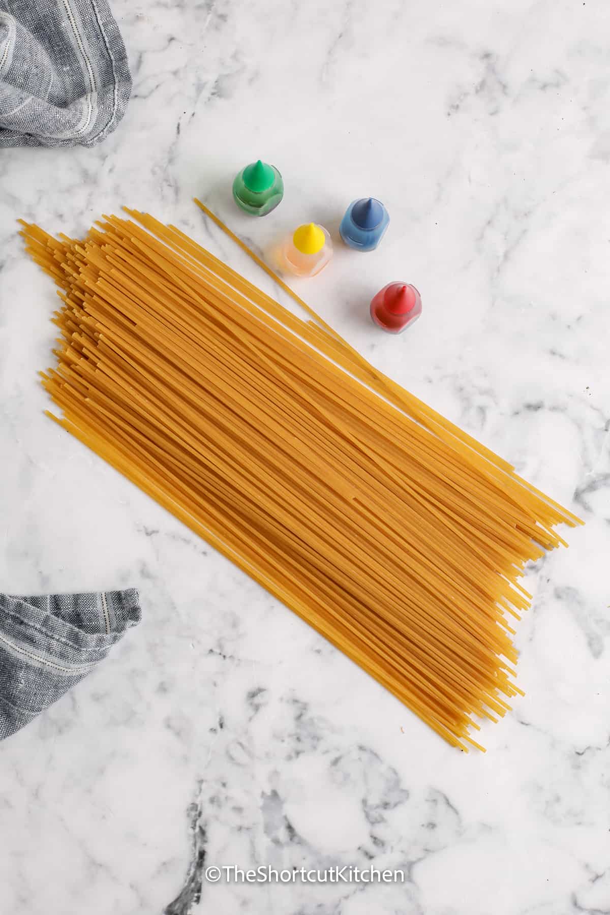 uncooked spaghetti noodles and four colours of food colouring