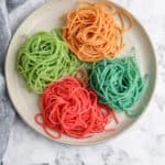 top view of red, green, blue, and orange spaghetti noodles on a plate