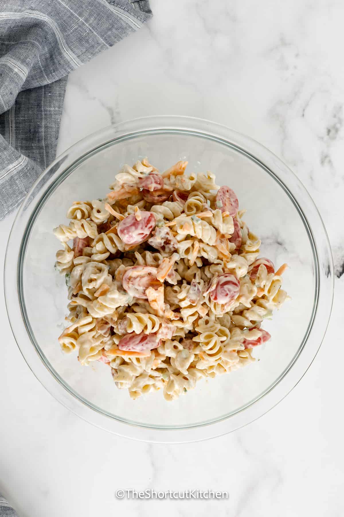 bacon ranch pasta salad being mixed in a bowl