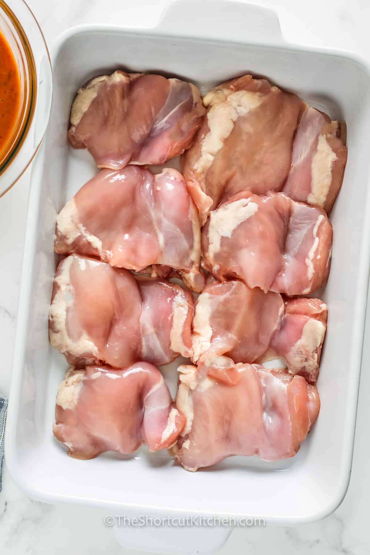 This easy apricot chicken recipe uses just 4 ingredients for big flavor. Apricot jam, Russian or French dressing, and onion soup mix create that sweet-and-savory Russian chicken sauce that clings to every bite. Bake chicken thighs, drumsticks, or breasts in one dish and serve with rice and a veggie. Freezer-friendly leftovers make this a repeat dinner win. #theshortcutkitchen chicken in a pan to make Apricot Chicken