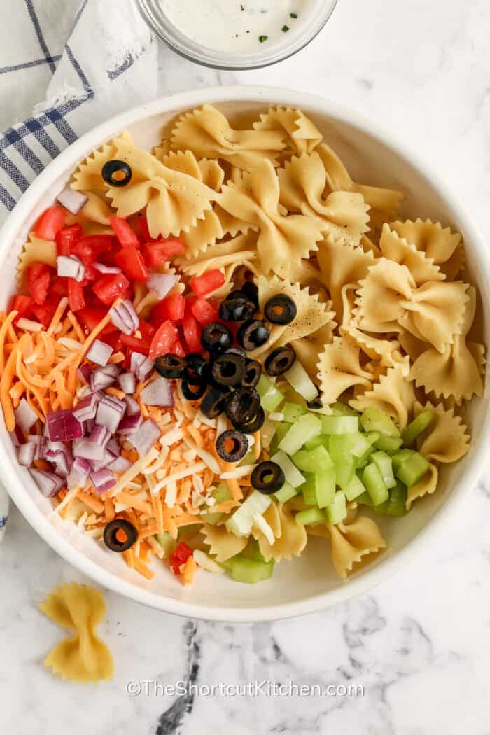 ingredients for bow tie pasta salad in a bowl