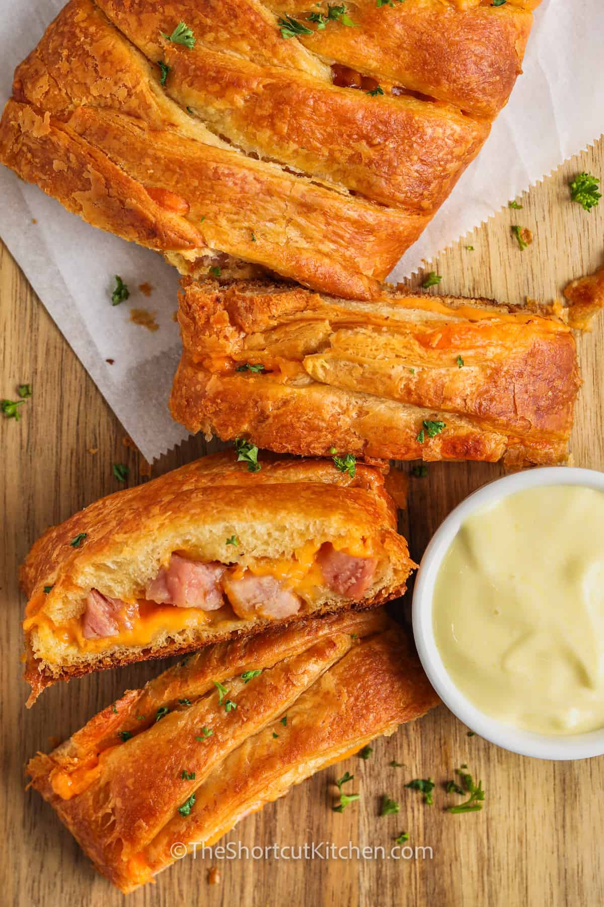 Ham & Cheese Crescent Braid cut into slices on a wooden board