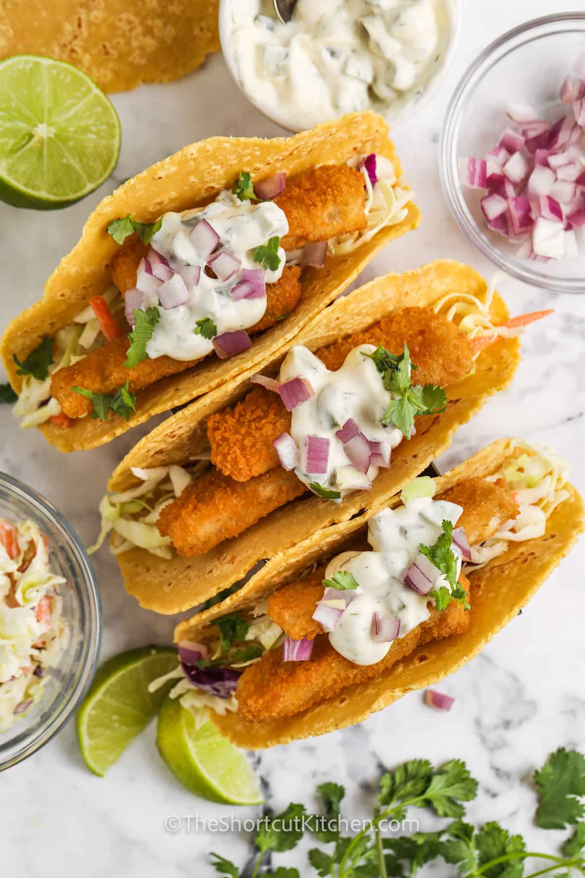 top view of Fish Stick Tacos with bowls of ingredients around them