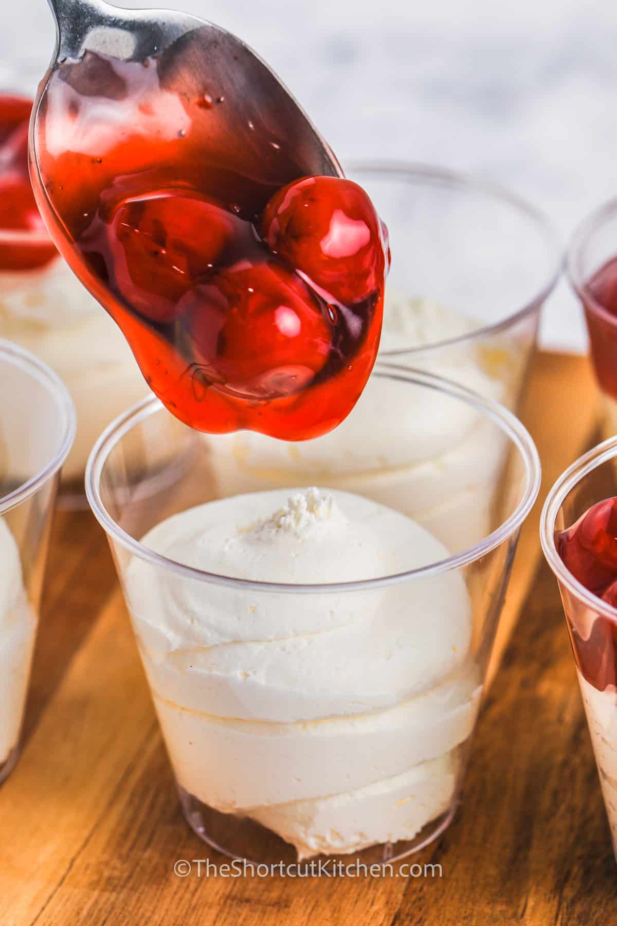 adding cherries to cup to make 3 Ingredient No Bake Cheesecake Cups