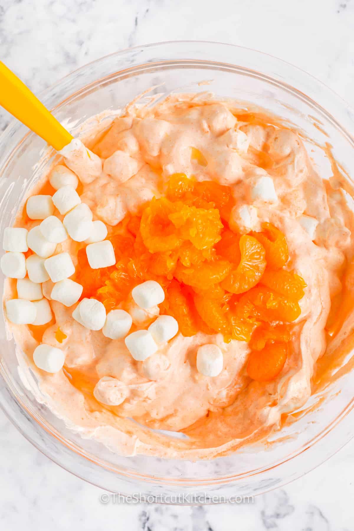 adding oranges and marshmallows to bowl to make Cottage Cheese Orange Jello Salad