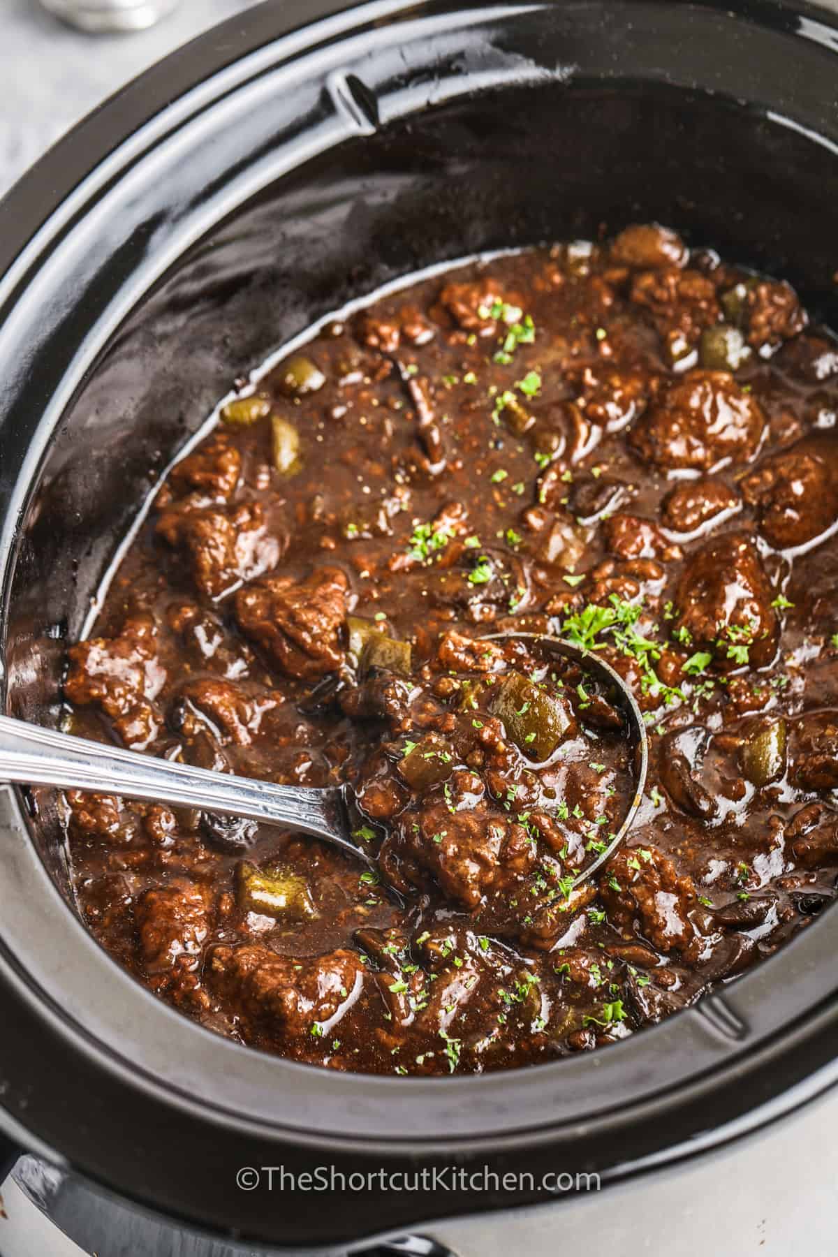 taking a spoonful of Crock Pot Beef And Gravy out of the pot