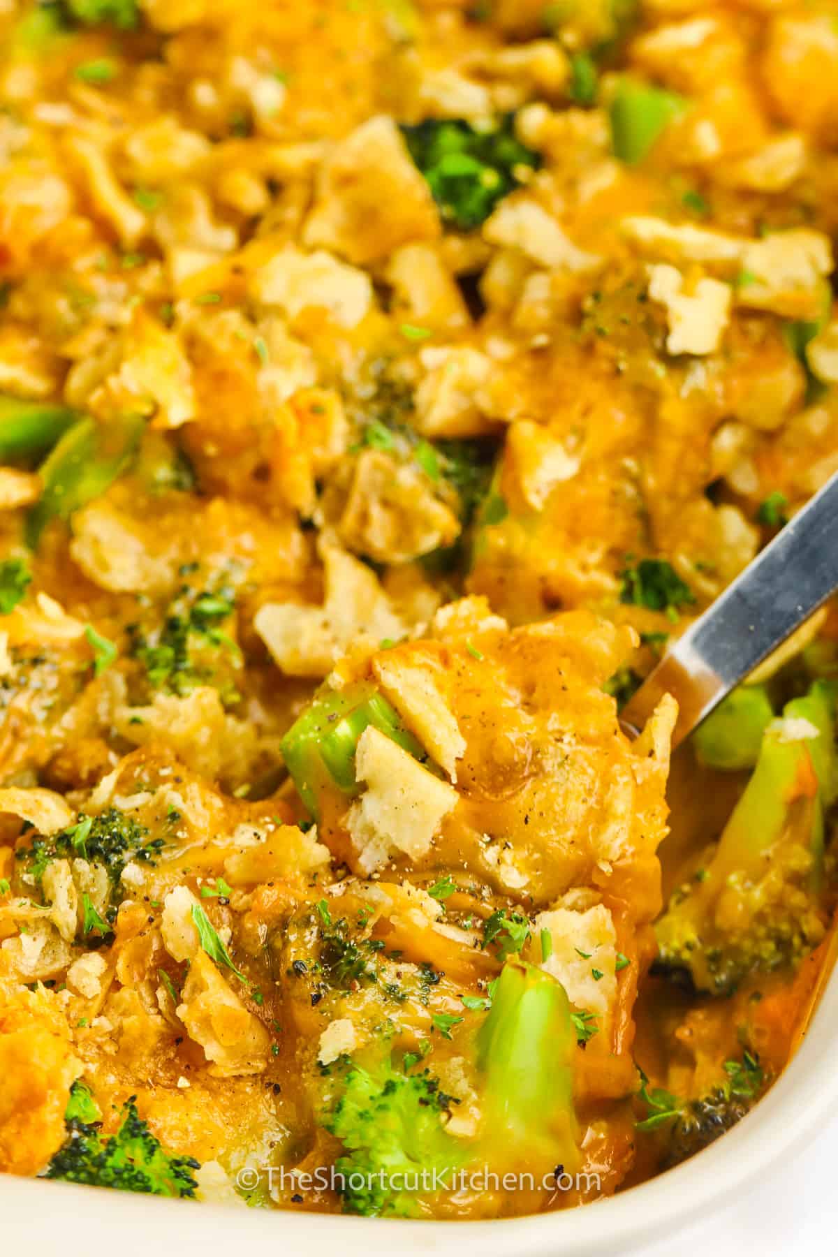 taking a spoonful of Baked Broccoli and Cheese Casserole from the dish