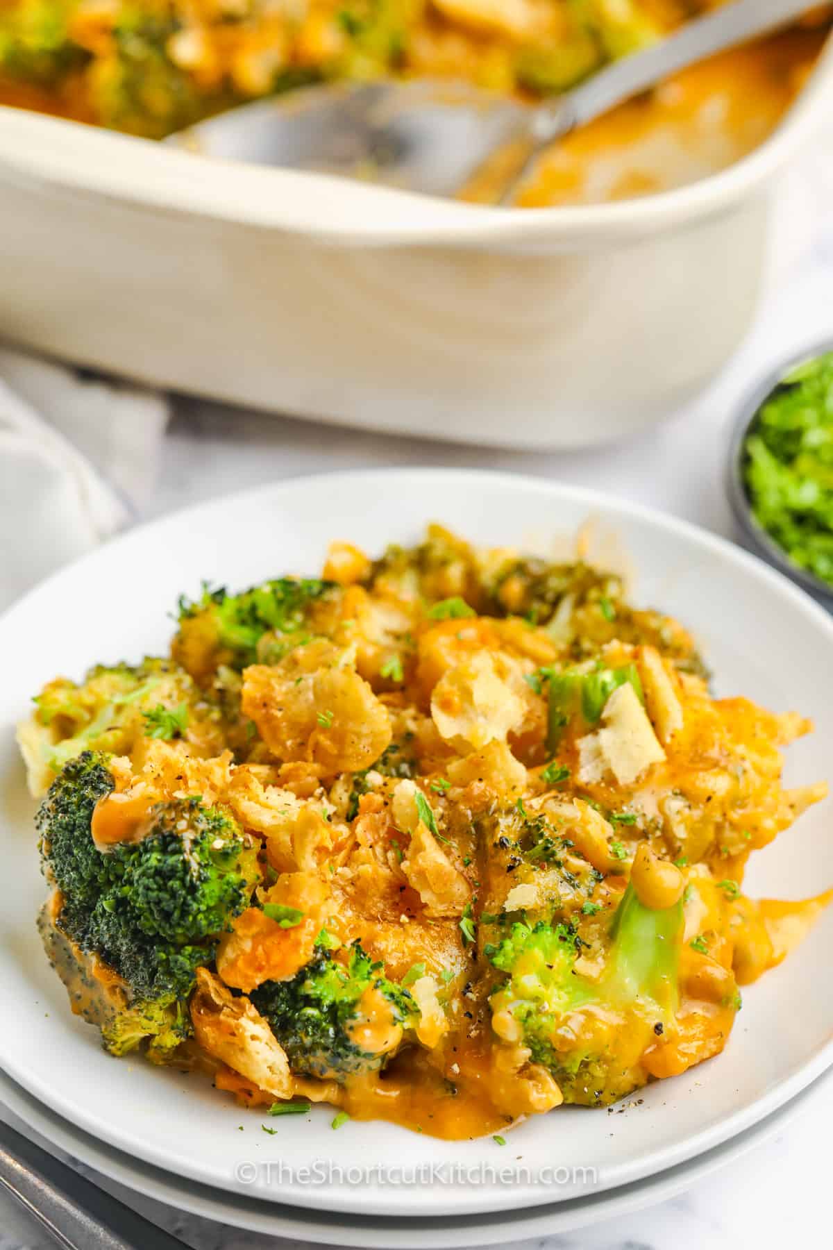 plated Baked Broccoli and Cheese Casserole with dish in the back