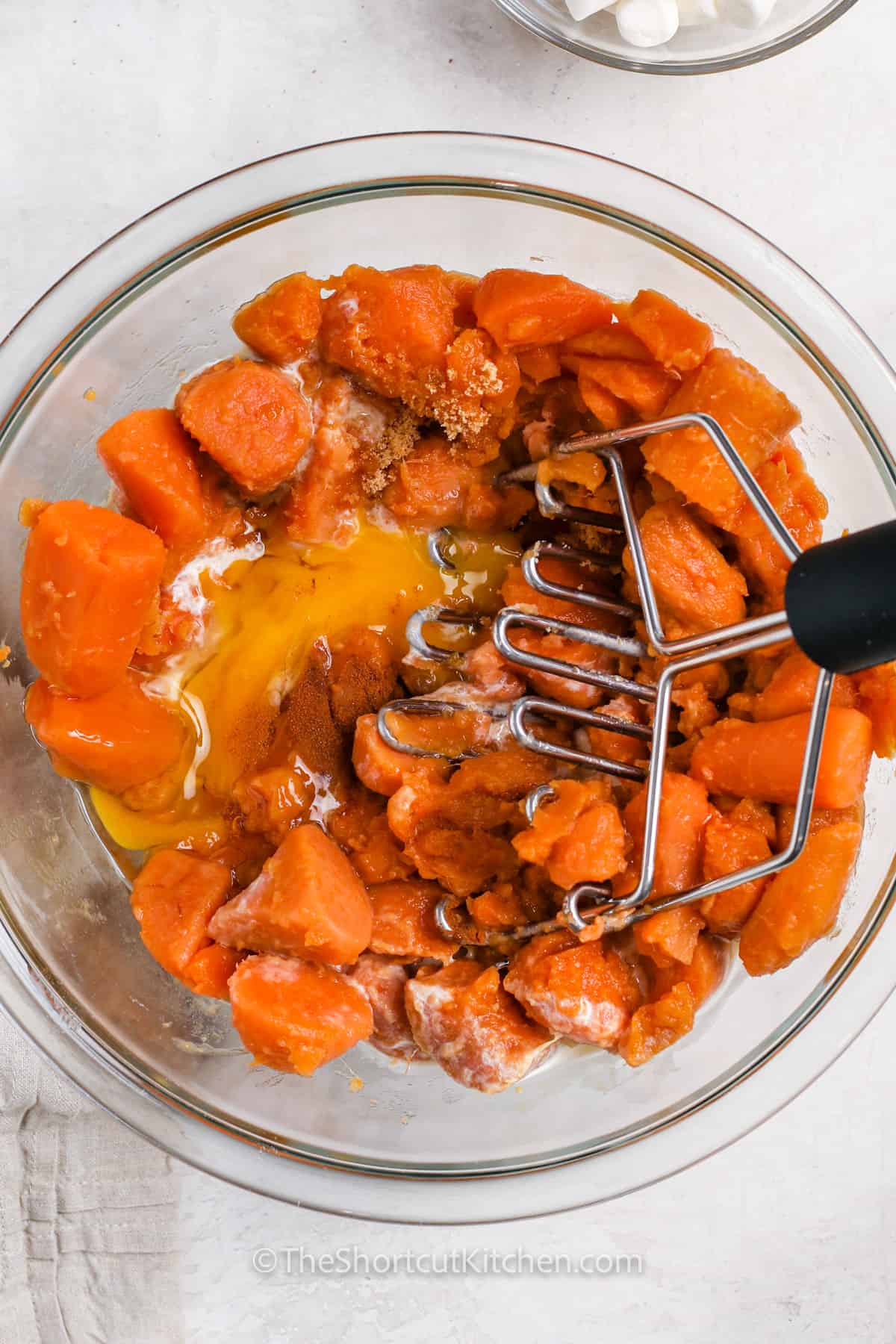 mashing ingredients together to make Canned Sweet Potato Casserole
