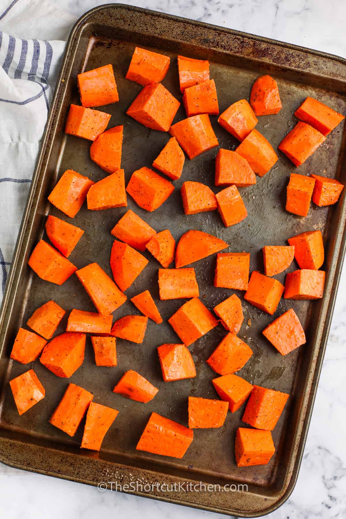 sweet potatoes seasoned on a sheet pan to make Oven Roasted Sweet Potatoes