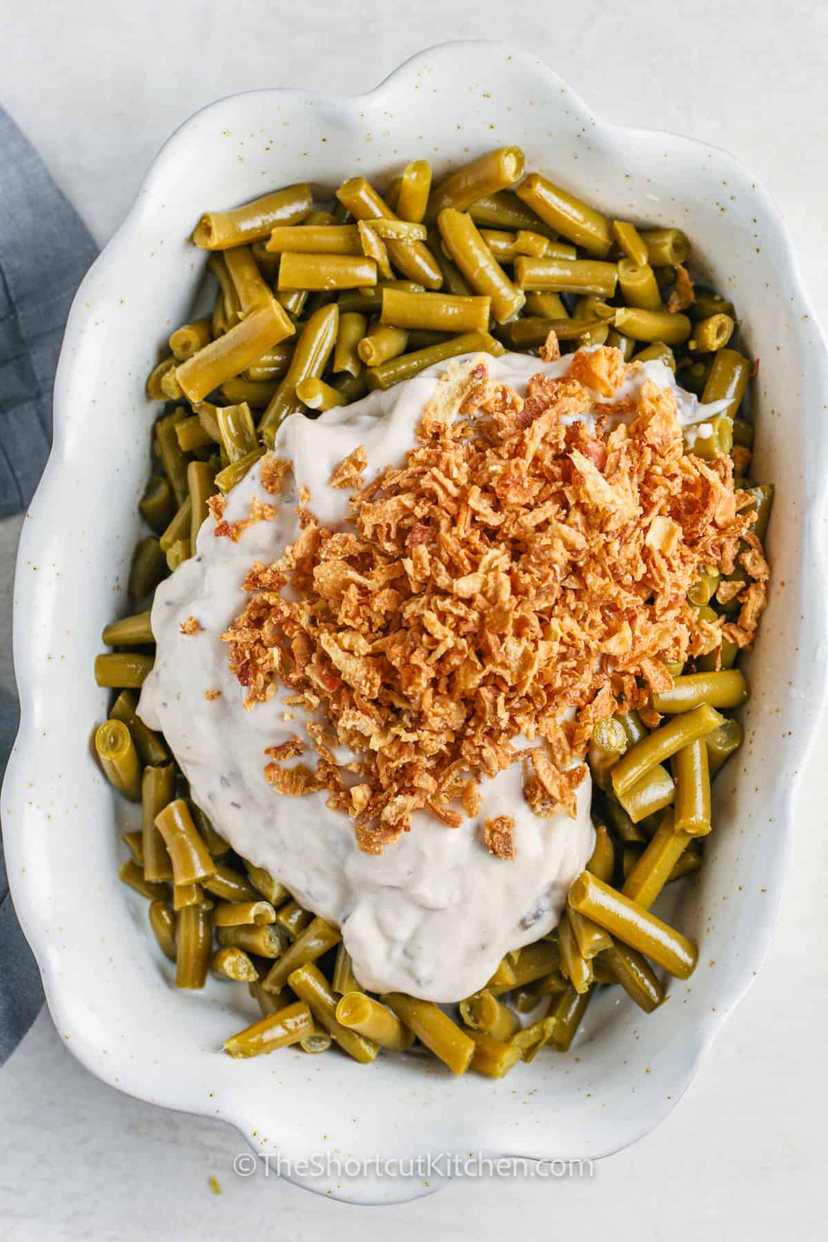 adding ingredients to green beans to make Canned Green Bean Casserole