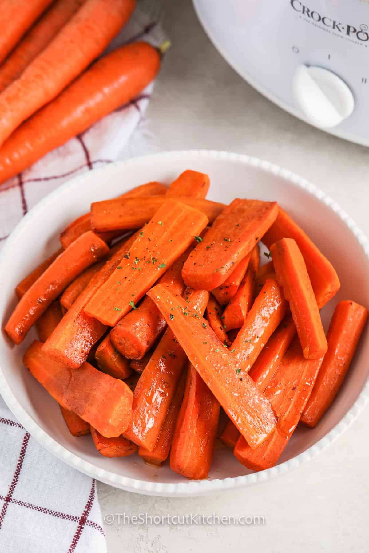 Crockpot carrots are a family favorite side dish because they are sweet, buttery, and so easy. This crock pot carrots recipe uses fresh carrots and pantry staples to make a cinnamon brown sugar glaze with almost no effort. Perfect for holidays, Sunday dinners, or meal prep. Serve these slow cooker carrots with roast beef, ham, chicken thighs, or meatloaf for a complete meal. #theshortcutkitchen Crockpot Carrots in a bowl