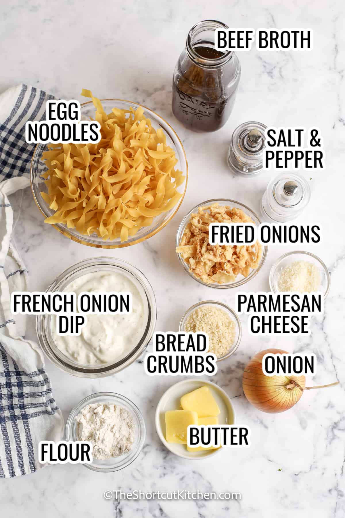 ingredients assembled to make french onion casserole, including egg noodles, beef broth, french onion dip, onion, and bread crumbs