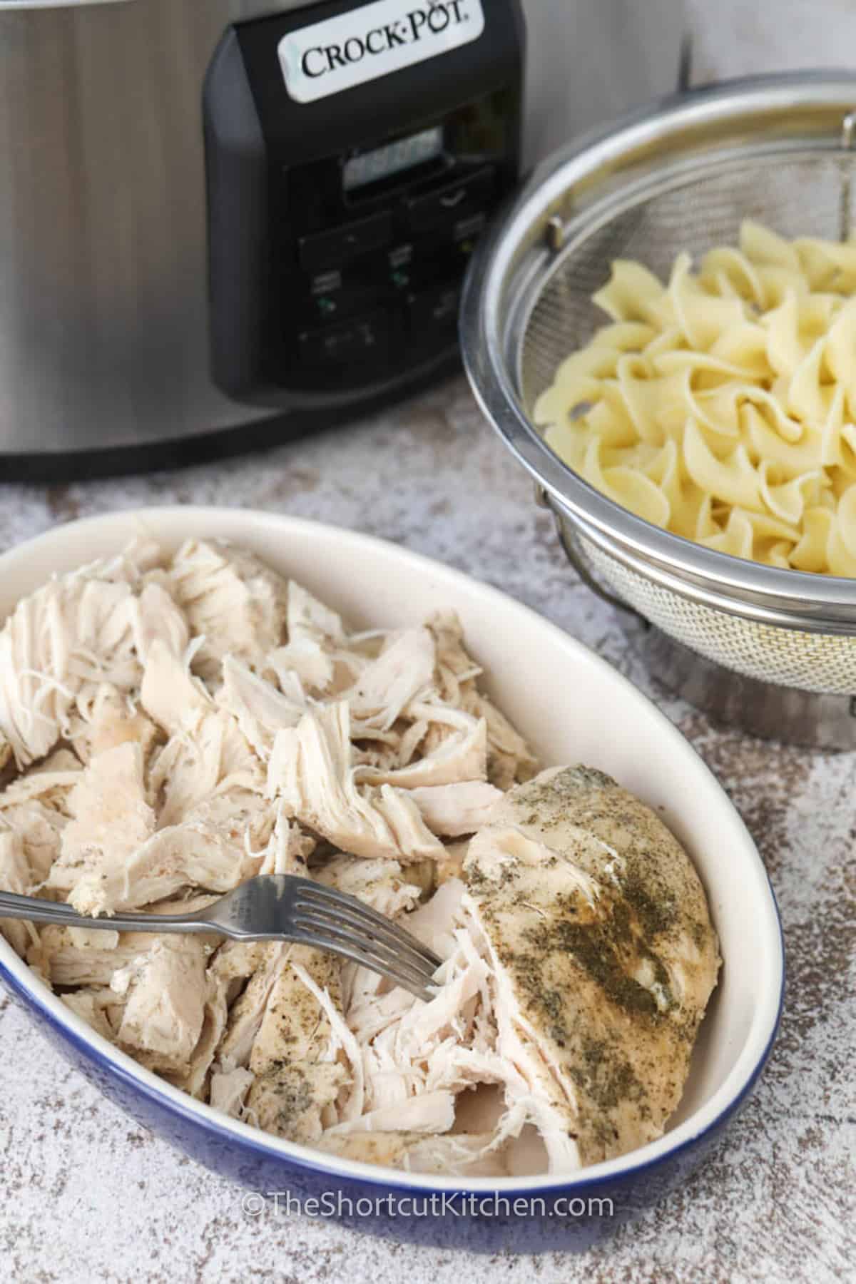 shredding chicken to make Crockpot Chicken Noodle Soup